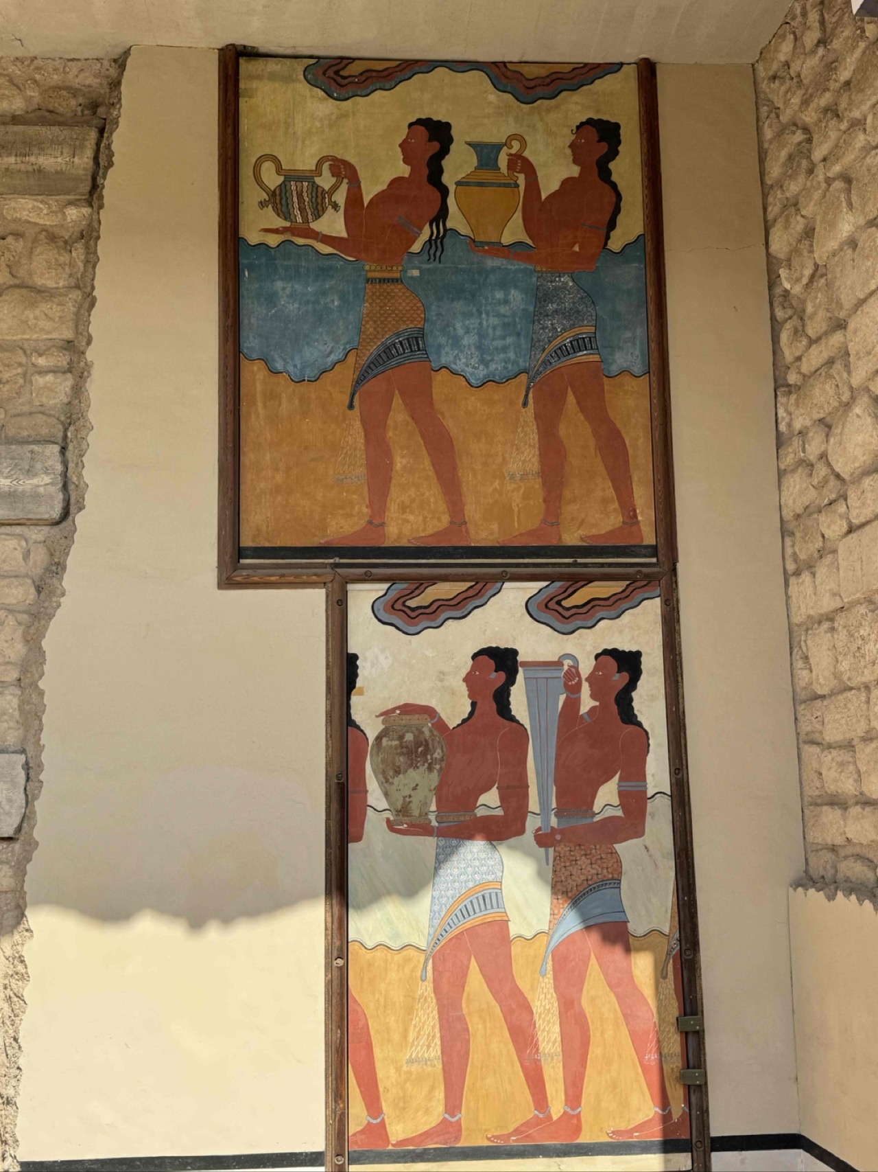 Reproductions of the famous Procession Fresco at Knossos, depicting figures carrying ceremonial vessels — note the detailed patterned kilts and rhyton (libation vessel). All the real frescos were moved to the Archaelogical Museum